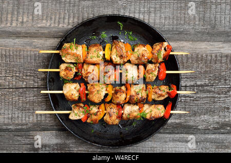 Grigliata di spiedini di pollo con verdure sul tavolo di legno, vista dall'alto Foto Stock