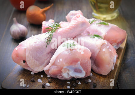 Il pollo crudo cosce di pollo disossate e spezie sul tagliere di legno Foto Stock