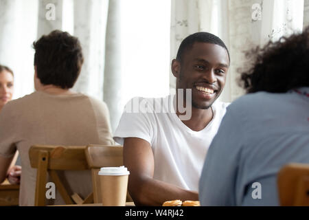 Sorridenti black ragazzo seduto in coffeehouse con un amico. Foto Stock