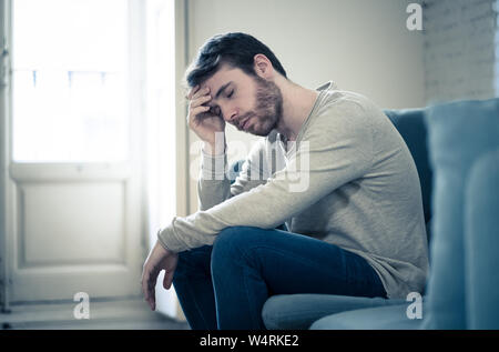 Premuto infelice maschio caucasico seduto o disteso in divano sensazione disperata un solitario che soffrono di depressione. In sottolineato dal lavoro, una Foto Stock