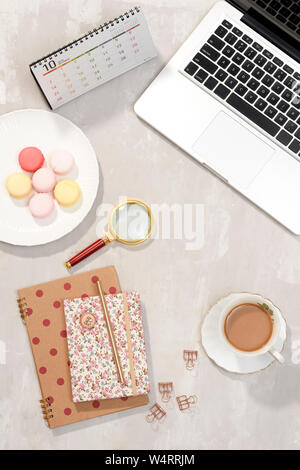 Area di lavoro con computer portatile, notebook, occhiali, una tazza di caffè e lisianthus fiori su sfondo grigio. Vista superiore femminile tabella office desk. Libero professionista wor Foto Stock