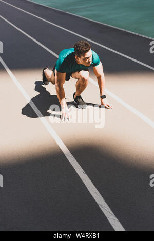 Bella gara di misto sportivo sulla posizione di avviamento che guarda lontano a Stadium Foto Stock