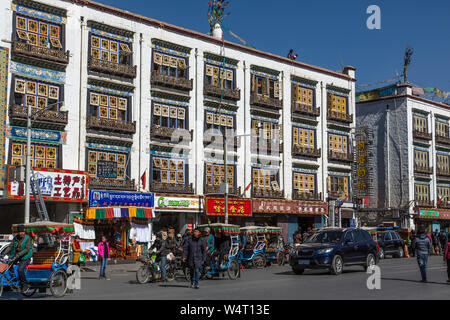 Cina, Tibet, Lhasa, Pedicabs attendere di fronte appartamenti moderni con disegni tradizionali. Foto Stock