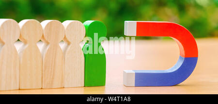 Figure in legno di persone e di un magnete. Gestione dei Team concetto. Risorse umane. Promuovere. La scelta di un nuovo leader e di assunzione dei dipendenti al lavoro. Headhunt Foto Stock