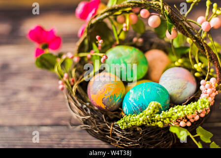 Uova di Pasqua in un cesto su un tavolo di legno Foto Stock