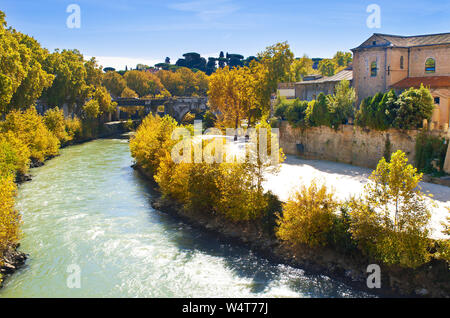 Vista del bianco Ponte Palatino ponte e case circostanti di Isola Tiberina, giallo alberi, acque del fiume Tevere sotto il blu limpido cielo di autunno Foto Stock