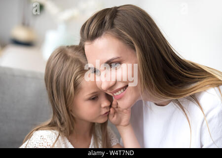 Figlia whispering per mamme orecchio un segreto Foto Stock