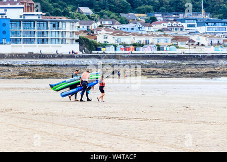 Una famiglia di surfers e bodyboarder voce per il mare sulla spiaggia di sabbia a Condino, Devon, Regno Unito Foto Stock