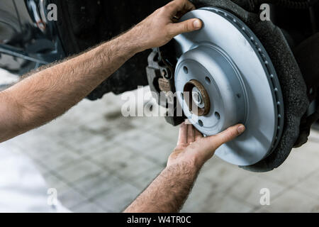 Vista ritagliata della vettura di contenimento meccanico metallico freno auto nei pressi di automobile Foto Stock