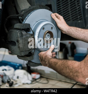 Vista ritagliata della auto meccanico metallico di contenimento del freno auto vicino a auto Foto Stock