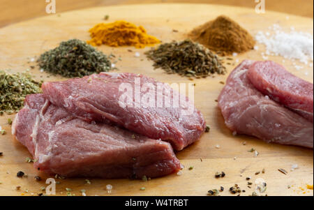 Materie non cotti fette di carne sul tavolo di legno con spezie Foto Stock