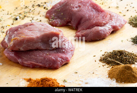 Materie non cotti fette di carne sul tavolo di legno con spezie Foto Stock