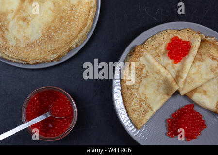 Blini triangoli o crepes con caviale rosso sulla piastra con i jar Foto Stock