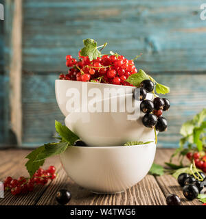 Fresche e mature rosso Ribes berry in bianco bocce stand in una pila sul tavolo. Cornice quadrata S Foto Stock