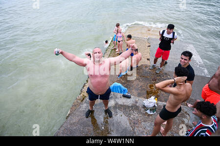 Brighton Regno Unito 25 luglio 2019 - Giovani uomini tuffarsi in mare da un groyne sulla spiaggia di Brighton come visitatori godere un altro caldo giorno di sole nel regno unito con forecasters predire le temperature record per parti del sud-est . Credito : Simon Dack / Alamy Live News Foto Stock
