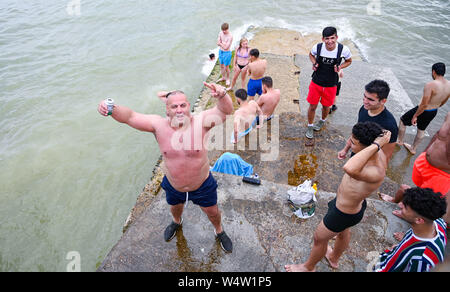 Brighton Regno Unito 25 luglio 2019 - Giovani uomini tuffarsi in mare da un groyne sulla spiaggia di Brighton come visitatori godere un altro caldo giorno di sole nel regno unito con forecasters predire le temperature record per parti del sud-est . Credito : Simon Dack / Alamy Live News Foto Stock