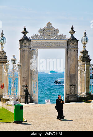 Istanbul, Turchia - 05/25/2010: musulmana donna vestita di nero indossa foulard di testa e il soldato di guardia alla porta nella parte anteriore del Bosforo stretto in dolmabahce pala Foto Stock