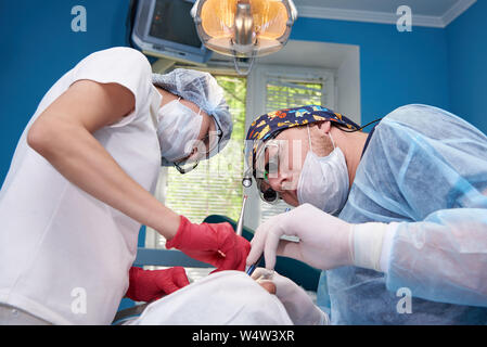 I medici di eseguire una operazione in una clinica dentale. Foto Stock