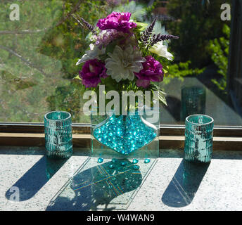 Bouquet di fiori in un vaso di vetro crea riflessi e ombre Foto Stock