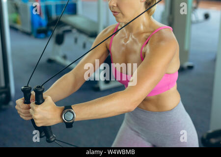 Atleta femminile esercizio con cavo crossover in macchina fitness studio Foto Stock