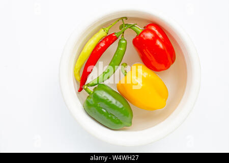 Diversi colori i peperoni e peperoncino imbevuto di acqua. Lavaggio verdure fresche su bianco Foto Stock