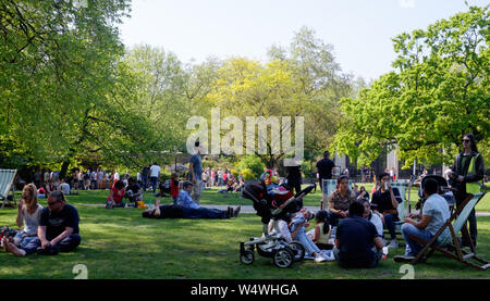 I londinesi e turisti sit e giacciono sull'erba godendo il giorno caldo e soleggiato al St James Park, Londra Centrale. Foto Stock