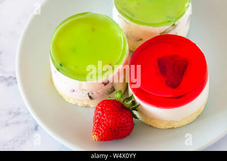 Mini rotonda la cheesecake a freddo con gelatina di frutta e le fragole. Foto Stock