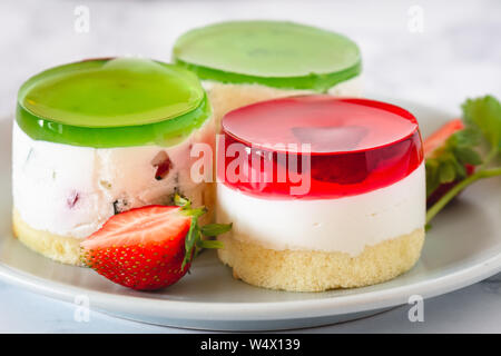 Mini rotonda la cheesecake a freddo con gelatina di frutta e le fragole. Foto Stock