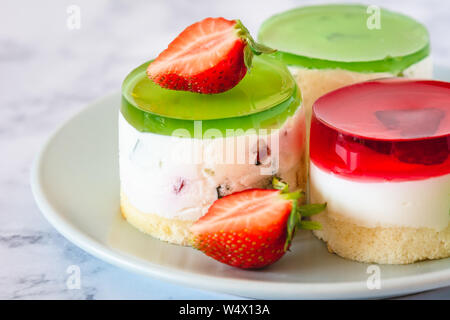 Mini rotonda la cheesecake a freddo con gelatina di frutta e le fragole. Foto Stock