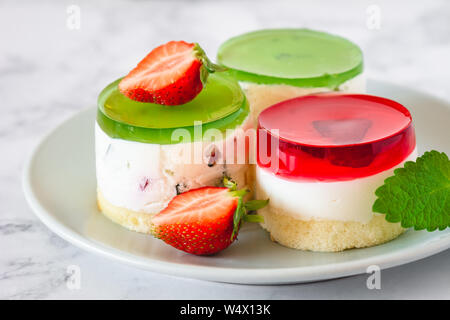 Mini rotonda la cheesecake a freddo con gelatina di frutta e le fragole. Foto Stock