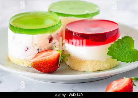 Mini rotonda la cheesecake a freddo con gelatina di frutta e le fragole. Foto Stock