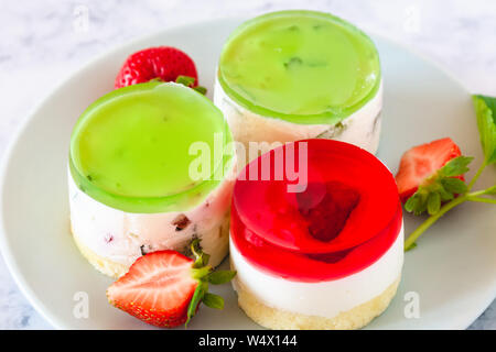 Mini rotonda la cheesecake a freddo con gelatina di frutta e le fragole. Foto Stock
