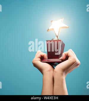 Foto di mani di uomo alzando il calice con star vuoto su sfondo blu Foto Stock