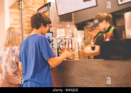 Giovane uomo ha ricevuto il suo pacchetto di cibo ordine in un fast food ristorante Foto Stock