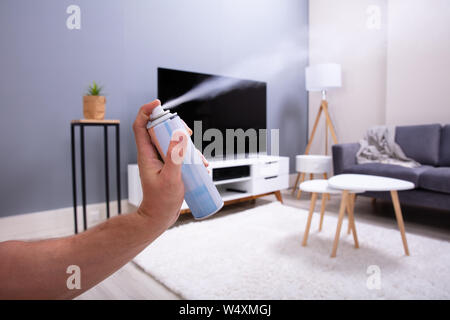 Close-up di mano di una persona spruzzare aria rinfrescante nel soggiorno Foto Stock