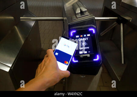 Uno smartphone con Google Wallet tocca un tornello della metropolitana di New York dotato di un lettore di pagamento senza contatto OMNY che accetta pagamenti NFC Foto Stock