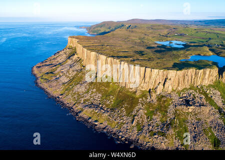 Fair Head big cliff e operazioni automatiche di fine campo all'angolo nord-est della Contea di Antrim, Irlanda del Nord, Regno Unito. Vista aerea nella luce del tramonto con oceano Atlantico un Foto Stock