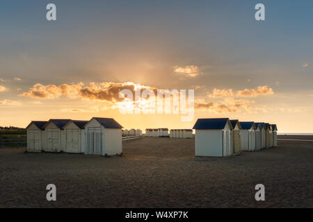 Riva Bella spiaggia tramonto panoramico con legno spiaggia bianca di capanne o cabine, Ouistreham, Normandia, Francia. Foto Stock