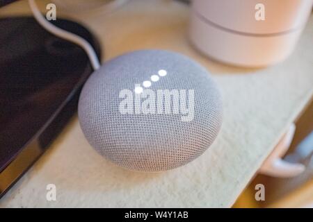 Close-up della Home page di Google Mini smart speaker con luci accese in una casa intelligente a San Ramon, in California, con Google Wifi rete mesh router in background, Marzo 26, 2019. () Foto Stock