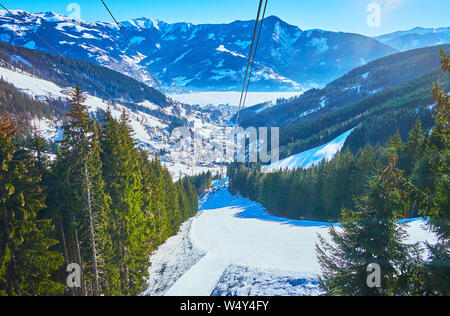 L'interessante viaggio sul cavo Schmittenhohenbahn auto con una vista sulle Alpi pendii innevati, piste, foreste e congelati lago Zeller See in valle, Zell am Foto Stock