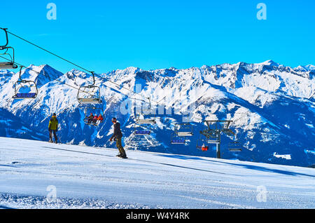 ZELL AM SEE, Austria - 28 febbraio 2019: lo snowboarder e sciatori godetevi il viaggio lungo il pendio del monte Schmittenhohe con una vista sul Kapell Foto Stock