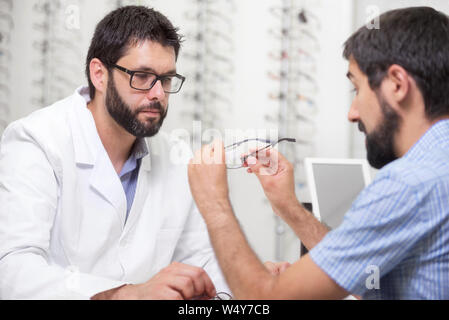 Oculista offrendo occhiali per provare. All'ottico optometrista offrendo di indossare un paio di occhiali . Foto Stock