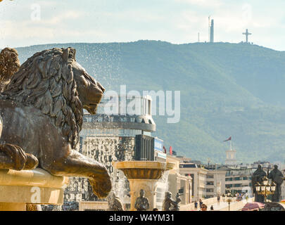 SKOPJE,Repubblica di Macedonia nord-Agosto 25 2018:Millennium Croce (fondo) guarda le statue e fontane al posto accanto alcarrello Museo di Foto Stock