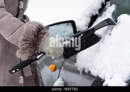 Mano nel guanto di pulizia auto da neve con una spazzola Foto Stock