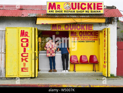 Roxas City, Capiz Provincia, Filippine: i giovani clienti in un colorato il sig. Quickie scarpa e borsa la riparazione e la chiave negozio di duplicati Foto Stock