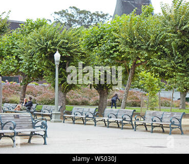 Due uomini rilassarsi e conversare mentre è seduto su una panchina nel parco. Foto Stock