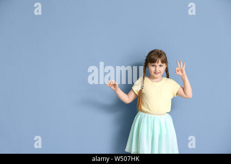 Carino sordomuto ragazza utilizzando il linguaggio dei segni sul colore di sfondo Foto Stock