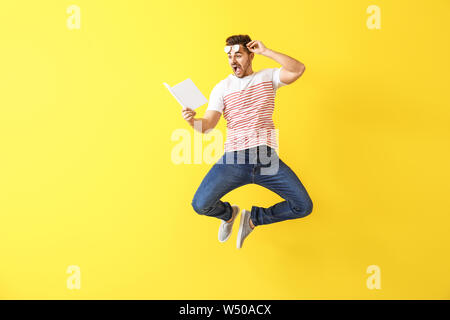 Jumping giovane con un libro sul colore di sfondo Foto Stock