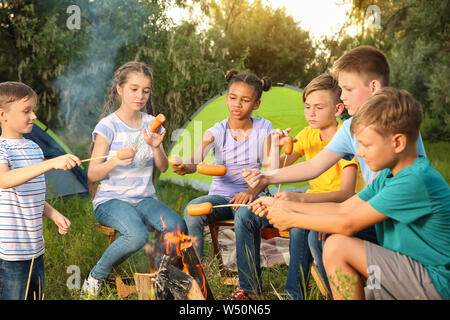 Gruppo di bambini la cottura di salsicce sul fuoco Foto Stock