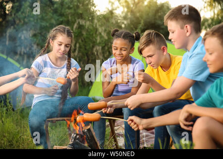 Gruppo di bambini la cottura di salsicce sul fuoco Foto Stock